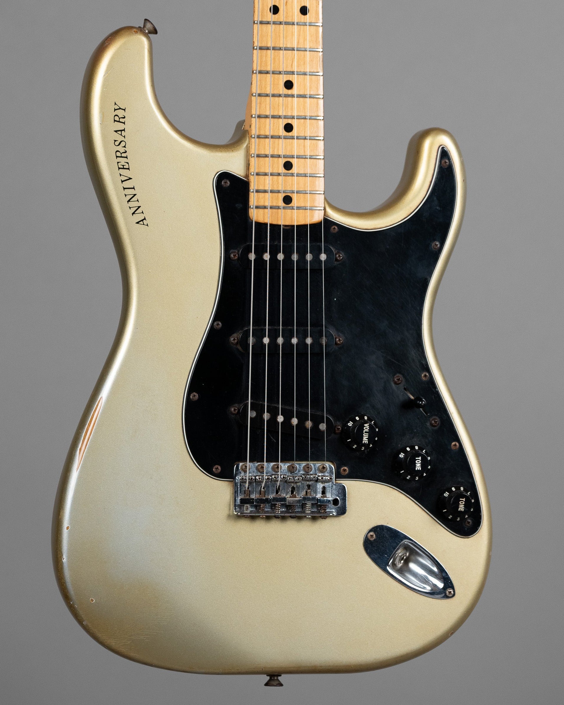 A 1979 Fender Anniversary Stratocaster electric guitar in silver with a black pickguard and aged appearance, displayed with the headstock facing forward.